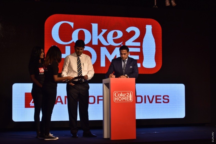 "ކޯކް ޓު ހޯމް" ގެ ނަމުގައި ކޮކާކޯލާ ކޮންޕެނީ އިން މުޅިން އައު އެޕްލިކޭޝަނެއް ތައާރަފް ކުރުމުގެ ގޮތުން ބޭއްވި ރަސްމިއްޔާތުގެ ތެރެއިން: އިފްތިތާހް ކުރެވިގެންދިޔަ އެޕްލިކޭޝަން ބޭނުންކޮށްގެން ކޮކާކޯލާ ކޮންޕެނީގެ ހުރިހާ އުފެއްދުންތަކެއް ބޭނުންވާ ތަނަކަށް އޯޑަރު ކުރުމުން 24 ގަޑީއިރުގެ ތެރޭގައި ޑެލިވަރީ ކޮށްދޭނެ----ސަން ފޮޓޯ 