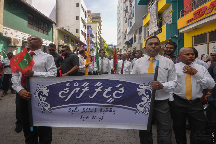 ޖުލައި 26، 2018: އިދިކޮޅު ރިޔާސީ ކެންޑިޑޭޓު އިބްރާހިމް މުހައްމަދު ސޯލިހު (އިބޫ) ގެ ކެންޑިޑެންސީ ފޯމު ހުށަހެޅުއްވުމަށް އިލެކްޝަންސް އަށް ވަޑައިގަންނަވަނީ: ގިނަ އަދަދެއްގެ ބަޔަކު އިބޫއާ އެކު އެމްޑީޕީ އޮފީހުން ފެށިގެން އިލެކްޝަންސް ކޮމިޝަނުގެ އިދާރާއަށް ގޮސްފައިވަނީ ބެރު ޖަހަމުން ހިނގާފައި  --- ސަންފޮޓޯ/ މުހައްމަދު އަފްރާހް