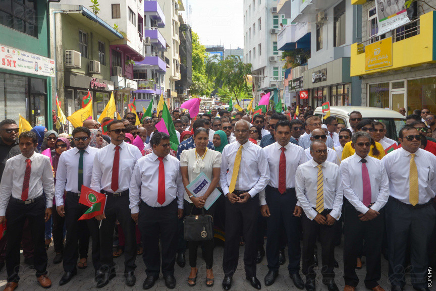 ޖުލައި 26، 2018: އިދިކޮޅު ރިޔާސީ ކެންޑިޑޭޓު އިބްރާހިމް މުހައްމަދު ސޯލިހު (އިބޫ) ގެ ކެންޑިޑެންސީ ފޯމު ހުށަހެޅުއްވުމަށް އިލެކްޝަންސް އަށް ވަޑައިގަންނަވަނީ: ގިނަ އަދަދެއްގެ ބަޔަކު އިބޫއާ އެކު އެމްޑީޕީ އޮފީހުން ފެށިގެން އިލެކްޝަންސް ކޮމިޝަނުގެ އިދާރާއަށް ގޮސްފައިވަނީ ބެރު ޖަހަމުން ހިނގާފައި  --- ސަންފޮޓޯ/ މުހައްމަދު އަފްރާހް