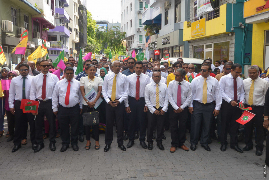 ޖުލައި 26، 2018: އިދިކޮޅު ރިޔާސީ ކެންޑިޑޭޓު އިބްރާހިމް މުހައްމަދު ސޯލިހު (އިބޫ) ގެ ކެންޑިޑެންސީ ފޯމު ހުށަހެޅުއްވުމަށް އިލެކްޝަންސް އަށް ވަޑައިގަންނަވަނީ: ގިނަ އަދަދެއްގެ ބަޔަކު އިބޫއާ އެކު އެމްޑީޕީ އޮފީހުން ފެށިގެން އިލެކްޝަންސް ކޮމިޝަނުގެ އިދާރާއަށް ގޮސްފައިވަނީ ބެރު ޖަހަމުން ހިނގާފައި  --- ސަންފޮޓޯ/ މުހައްމަދު އަފްރާހް