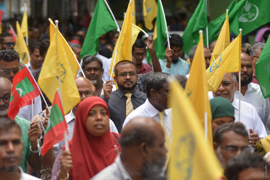 ޖުލައި 26، 2018: އިދިކޮޅު ރިޔާސީ ކެންޑިޑޭޓު އިބްރާހިމް މުހައްމަދު ސޯލިހު (އިބޫ) ގެ ކެންޑިޑެންސީ ފޯމު ހުށަހެޅުއްވުމަށް އިލެކްޝަންސް އަށް ވަޑައިގަންނަވަނީ: ގިނަ އަދަދެއްގެ ބަޔަކު އިބޫއާ އެކު އެމްޑީޕީ އޮފީހުން ފެށިގެން އިލެކްޝަންސް ކޮމިޝަނުގެ އިދާރާއަށް ގޮސްފައިވަނީ ބެރު ޖަހަމުން ހިނގާފައި  --- ސަންފޮޓޯ/ މުހައްމަދު އަފްރާހް