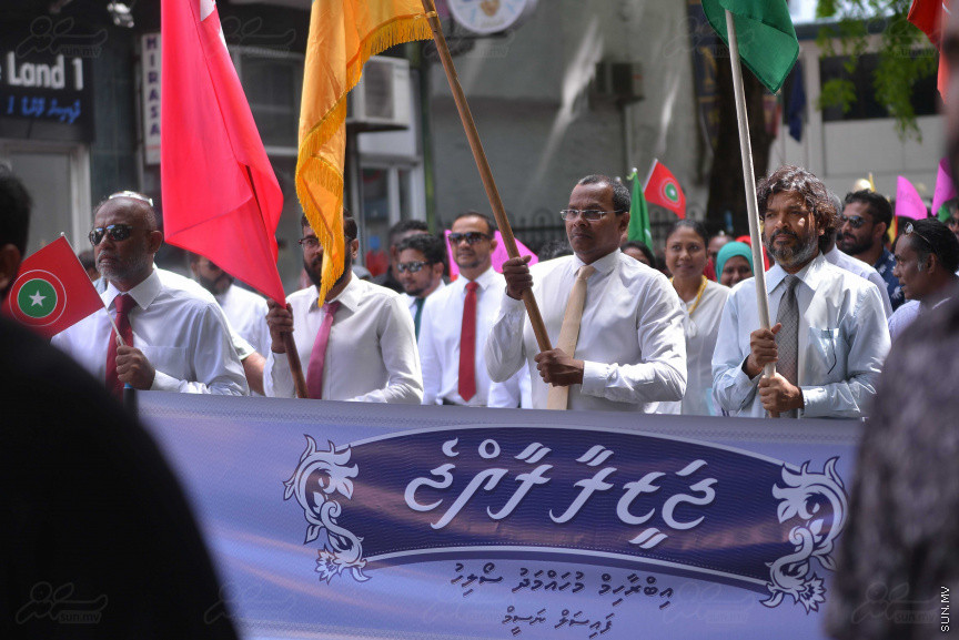 ޖުލައި 26، 2018: އިދިކޮޅު ރިޔާސީ ކެންޑިޑޭޓު އިބްރާހިމް މުހައްމަދު ސޯލިހު (އިބޫ) ގެ ކެންޑިޑެންސީ ފޯމު ހުށަހެޅުއްވުމަށް އިލެކްޝަންސް އަށް ވަޑައިގަންނަވަނީ: ގިނަ އަދަދެއްގެ ބަޔަކު އިބޫއާ އެކު އެމްޑީޕީ އޮފީހުން ފެށިގެން އިލެކްޝަންސް ކޮމިޝަނުގެ އިދާރާއަށް ގޮސްފައިވަނީ ބެރު ޖަހަމުން ހިނގާފައި  --- ސަންފޮޓޯ/ މުހައްމަދު އަފްރާހް