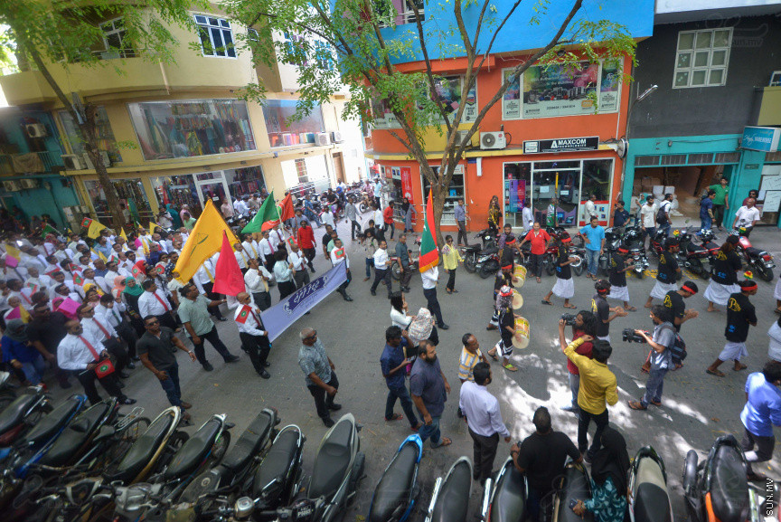 ޖުލައި 26، 2018: އިދިކޮޅު ރިޔާސީ ކެންޑިޑޭޓު އިބްރާހިމް މުހައްމަދު ސޯލިހު (އިބޫ) ގެ ކެންޑިޑެންސީ ފޯމު ހުށަހެޅުއްވުމަށް އިލެކްޝަންސް އަށް ވަޑައިގަންނަވަނީ: ގިނަ އަދަދެއްގެ ބަޔަކު އިބޫއާ އެކު އެމްޑީޕީ އޮފީހުން ފެށިގެން އިލެކްޝަންސް ކޮމިޝަނުގެ އިދާރާއަށް ގޮސްފައިވަނީ ބެރު ޖަހަމުން ހިނގާފައި  --- ސަންފޮޓޯ/ މުހައްމަދު އަފްރާހް