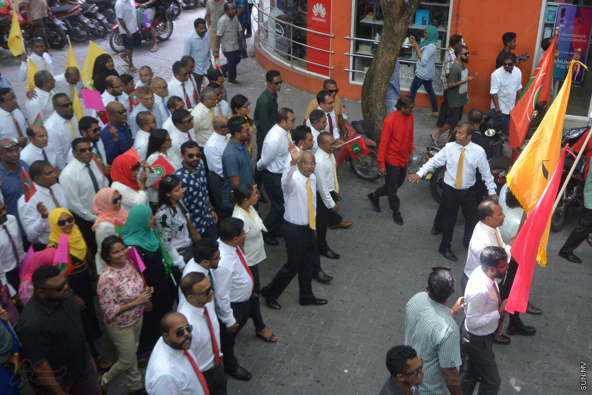 ޖުލައި 26، 2018: އިދިކޮޅު ރިޔާސީ ކެންޑިޑޭޓު އިބްރާހިމް މުހައްމަދު ސޯލިހު (އިބޫ) ގެ ކެންޑިޑެންސީ ފޯމު ހުށަހެޅުއްވުމަށް އިލެކްޝަންސް އަށް ވަޑައިގަންނަވަނީ: ގިނަ އަދަދެއްގެ ބަޔަކު އިބޫއާ އެކު އެމްޑީޕީ އޮފީހުން ފެށިގެން އިލެކްޝަންސް ކޮމިޝަނުގެ އިދާރާއަށް ގޮސްފައިވަނީ ބެރު ޖަހަމުން ހިނގާފައި  --- ސަންފޮޓޯ/ މުހައްމަދު އަފްރާހް