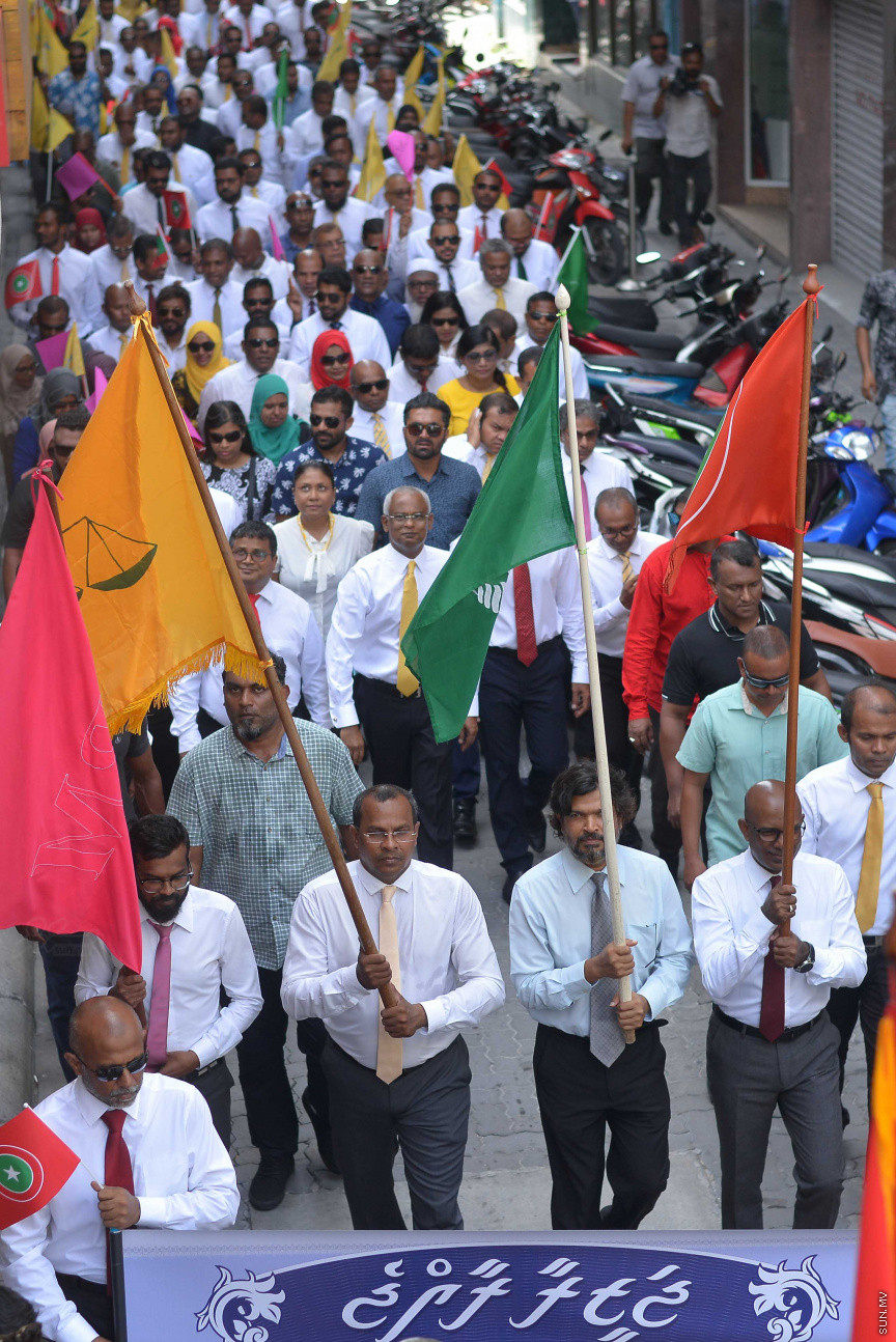 ޖުލައި 26، 2018: އިދިކޮޅު ރިޔާސީ ކެންޑިޑޭޓު އިބްރާހިމް މުހައްމަދު ސޯލިހު (އިބޫ) ގެ ކެންޑިޑެންސީ ފޯމު ހުށަހެޅުއްވުމަށް އިލެކްޝަންސް އަށް ވަޑައިގަންނަވަނީ: ގިނަ އަދަދެއްގެ ބަޔަކު އިބޫއާ އެކު އެމްޑީޕީ އޮފީހުން ފެށިގެން އިލެކްޝަންސް ކޮމިޝަނުގެ އިދާރާއަށް ގޮސްފައިވަނީ ބެރު ޖަހަމުން ހިނގާފައި  --- ސަންފޮޓޯ/ މުހައްމަދު އަފްރާހް