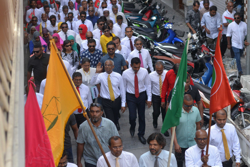 ޖުލައި 26، 2018: އިދިކޮޅު ރިޔާސީ ކެންޑިޑޭޓު އިބްރާހިމް މުހައްމަދު ސޯލިހު (އިބޫ) ގެ ކެންޑިޑެންސީ ފޯމު ހުށަހެޅުއްވުމަށް އިލެކްޝަންސް އަށް ވަޑައިގަންނަވަނީ: ގިނަ އަދަދެއްގެ ބަޔަކު އިބޫއާ އެކު އެމްޑީޕީ އޮފީހުން ފެށިގެން އިލެކްޝަންސް ކޮމިޝަނުގެ އިދާރާއަށް ގޮސްފައިވަނީ ބެރު ޖަހަމުން ހިނގާފައި  --- ސަންފޮޓޯ/ މުހައްމަދު އަފްރާހް