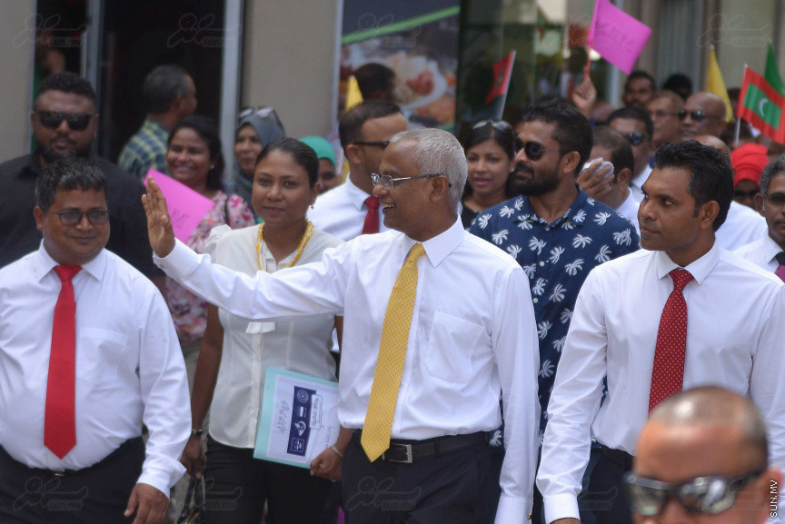 ޖުލައި 26، 2018: އިދިކޮޅު ރިޔާސީ ކެންޑިޑޭޓު އިބްރާހިމް މުހައްމަދު ސޯލިހު (އިބޫ) ގެ ކެންޑިޑެންސީ ފޯމު ހުށަހެޅުއްވުމަށް އިލެކްޝަންސް އަށް ވަޑައިގަންނަވަނީ: ގިނަ އަދަދެއްގެ ބަޔަކު އިބޫއާ އެކު އެމްޑީޕީ އޮފީހުން ފެށިގެން އިލެކްޝަންސް ކޮމިޝަނުގެ އިދާރާއަށް ގޮސްފައިވަނީ ބެރު ޖަހަމުން ހިނގާފައި  --- ސަންފޮޓޯ/ މުހައްމަދު އަފްރާހް