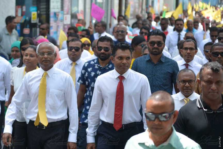 ޖުލައި 26، 2018: އިދިކޮޅު ރިޔާސީ ކެންޑިޑޭޓު އިބްރާހިމް މުހައްމަދު ސޯލިހު (އިބޫ) ގެ ކެންޑިޑެންސީ ފޯމު ހުށަހެޅުއްވުމަށް އިލެކްޝަންސް އަށް ވަޑައިގަންނަވަނީ: ގިނަ އަދަދެއްގެ ބަޔަކު އިބޫއާ އެކު އެމްޑީޕީ އޮފީހުން ފެށިގެން އިލެކްޝަންސް ކޮމިޝަނުގެ އިދާރާއަށް ގޮސްފައިވަނީ ބެރު ޖަހަމުން ހިނގާފައި  --- ސަންފޮޓޯ/ މުހައްމަދު އަފްރާހް