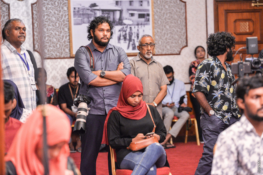 މާޗް 27، 2020: ކޮވިޑް19ގެ ނުރައްކާ ރާއްޖެއަށް ބޮޑުވެ، މުޅި ރާއްޖޭގައި ސިއްހީ ކުއްލި ނުރައްކާ އިއުލާން ކުރީ މި މަހުގެ 12 ވަނަ ދުވަހުއެވެ. އޭގެ ކުރިން ވެސް ކޮވިޑް19ގެ ހާލަތު އޮތް މިންވަރު ސަރުކާރުން ދިޔައީ ބުނެދެމުންނެވެ. ކޮވިޑް-19ގެ ތަރުޖާމާނެއްގެ ގޮތުގުގައި ރައީސް އޮފީހުގެ އަންޑަ ސެކްރެޓަރީ މަބްރޫކް އަބްދުލް އަޒީޒް ކަނޑައެޅުމާ އެކު ކޮންމެ ދުވަހަކު އެ ބޭފުޅާ ގެންދަވަނީ މީޑިއާތަކަށް މައުލޫމާތު ދެއްވަމުންނެވެ. ހުކުރު ދުވަސް ފިޔަވައި ކޮންމެ ދުވަަކު ދެ އިރު ޕްރެސް ކޮންފަރެންސް ދެއްވައެވެ. ހުކުރު ދުވަހުގެ ރޭ ވެސް ޕްރެސް ދެއްވައެވެ. ސަރުކާރު ބަންދުކޮށް، ކެފޭތަކާއި ރެސްޓޯރަންތުތައް ބަންދުކޮށްފައިވުމުން، ގޭގައި ތިބެގެން ގިނަ ބަޔަކު މަބްރޫކް ބާއްވާ ޕްރެސް ކޮންފަރެންސްތައް ދަނީ ބަލަމުންނެވެ. މި ފޮޓޯތަކުން މި ފެންނަނީ އެ ޕްރެސް ކޮންފަރެންސްތަކުގެ އަނެއް ފަރާތެވެ -- ސަން ފޮޓޯ/ ފަޔާޒު މޫސާ
