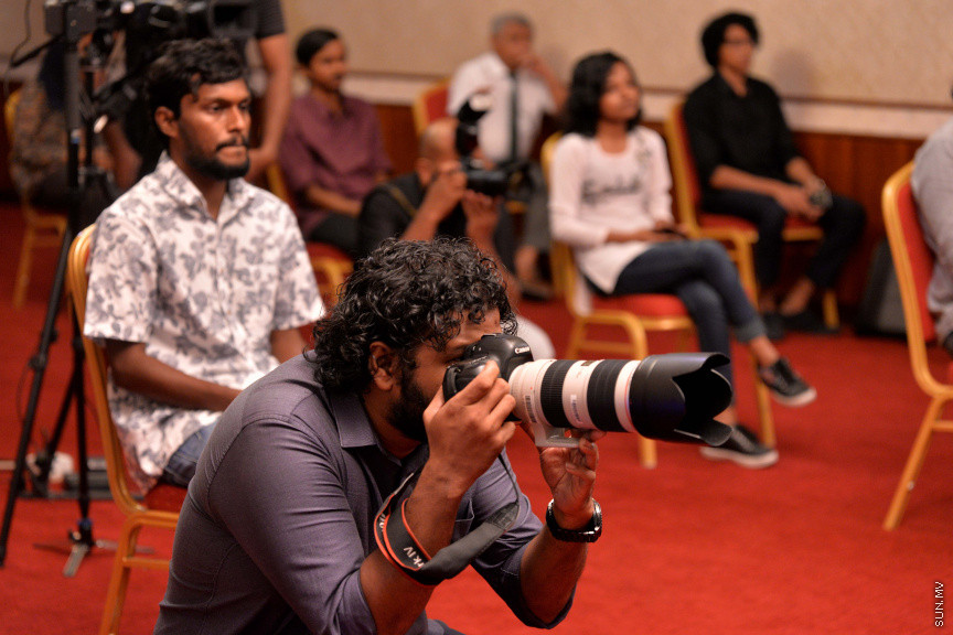 މާޗް 27، 2020: ކޮވިޑް19ގެ ނުރައްކާ ރާއްޖެއަށް ބޮޑުވެ، މުޅި ރާއްޖޭގައި ސިއްހީ ކުއްލި ނުރައްކާ އިއުލާން ކުރީ މި މަހުގެ 12 ވަނަ ދުވަހުއެވެ. އޭގެ ކުރިން ވެސް ކޮވިޑް19ގެ ހާލަތު އޮތް މިންވަރު ސަރުކާރުން ދިޔައީ ބުނެދެމުންނެވެ. ކޮވިޑް-19ގެ ތަރުޖާމާނެއްގެ ގޮތުގުގައި ރައީސް އޮފީހުގެ އަންޑަ ސެކްރެޓަރީ މަބްރޫކް އަބްދުލް އަޒީޒް ކަނޑައެޅުމާ އެކު ކޮންމެ ދުވަހަކު އެ ބޭފުޅާ ގެންދަވަނީ މީޑިއާތަކަށް މައުލޫމާތު ދެއްވަމުންނެވެ. ހުކުރު ދުވަސް ފިޔަވައި ކޮންމެ ދުވަަކު ދެ އިރު ޕްރެސް ކޮންފަރެންސް ދެއްވައެވެ. ހުކުރު ދުވަހުގެ ރޭ ވެސް ޕްރެސް ދެއްވައެވެ. ސަރުކާރު ބަންދުކޮށް، ކެފޭތަކާއި ރެސްޓޯރަންތުތައް ބަންދުކޮށްފައިވުމުން، ގޭގައި ތިބެގެން ގިނަ ބަޔަކު މަބްރޫކް ބާއްވާ ޕްރެސް ކޮންފަރެންސްތައް ދަނީ ބަލަމުންނެވެ. މި ފޮޓޯތަކުން މި ފެންނަނީ އެ ޕްރެސް ކޮންފަރެންސްތަކުގެ އަނެއް ފަރާތެވެ -- ސަން ފޮޓޯ/ ފަޔާޒު މޫސާ