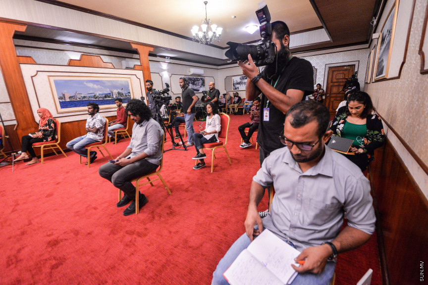 މާޗް 27، 2020: ކޮވިޑް19ގެ ނުރައްކާ ރާއްޖެއަށް ބޮޑުވެ، މުޅި ރާއްޖޭގައި ސިއްހީ ކުއްލި ނުރައްކާ އިއުލާން ކުރީ މި މަހުގެ 12 ވަނަ ދުވަހުއެވެ. އޭގެ ކުރިން ވެސް ކޮވިޑް19ގެ ހާލަތު އޮތް މިންވަރު ސަރުކާރުން ދިޔައީ ބުނެދެމުންނެވެ. ކޮވިޑް-19ގެ ތަރުޖާމާނެއްގެ ގޮތުގުގައި ރައީސް އޮފީހުގެ އަންޑަ ސެކްރެޓަރީ މަބްރޫކް އަބްދުލް އަޒީޒް ކަނޑައެޅުމާ އެކު ކޮންމެ ދުވަހަކު އެ ބޭފުޅާ ގެންދަވަނީ މީޑިއާތަކަށް މައުލޫމާތު ދެއްވަމުންނެވެ. ހުކުރު ދުވަސް ފިޔަވައި ކޮންމެ ދުވަަކު ދެ އިރު ޕްރެސް ކޮންފަރެންސް ދެއްވައެވެ. ހުކުރު ދުވަހުގެ ރޭ ވެސް ޕްރެސް ދެއްވައެވެ. ސަރުކާރު ބަންދުކޮށް، ކެފޭތަކާއި ރެސްޓޯރަންތުތައް ބަންދުކޮށްފައިވުމުން، ގޭގައި ތިބެގެން ގިނަ ބަޔަކު މަބްރޫކް ބާއްވާ ޕްރެސް ކޮންފަރެންސްތައް ދަނީ ބަލަމުންނެވެ. މި ފޮޓޯތަކުން މި ފެންނަނީ އެ ޕްރެސް ކޮންފަރެންސްތަކުގެ އަނެއް ފަރާތެވެ -- ސަން ފޮޓޯ/ ފަޔާޒު މޫސާ
