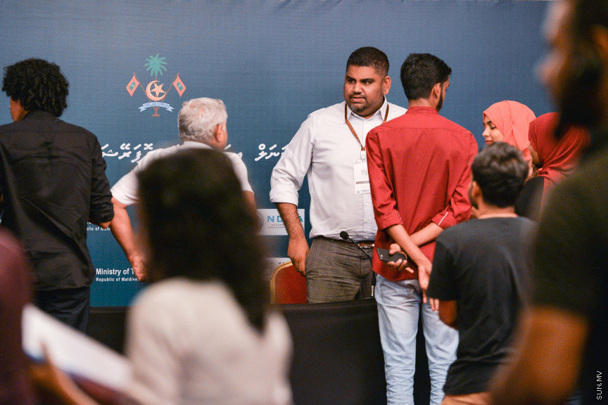 މާޗް 27، 2020: ކޮވިޑް19ގެ ނުރައްކާ ރާއްޖެއަށް ބޮޑުވެ، މުޅި ރާއްޖޭގައި ސިއްހީ ކުއްލި ނުރައްކާ އިއުލާން ކުރީ މި މަހުގެ 12 ވަނަ ދުވަހުއެވެ. އޭގެ ކުރިން ވެސް ކޮވިޑް19ގެ ހާލަތު އޮތް މިންވަރު ސަރުކާރުން ދިޔައީ ބުނެދެމުންނެވެ. ކޮވިޑް-19ގެ ތަރުޖާމާނެއްގެ ގޮތުގުގައި ރައީސް އޮފީހުގެ އަންޑަ ސެކްރެޓަރީ މަބްރޫކް އަބްދުލް އަޒީޒް ކަނޑައެޅުމާ އެކު ކޮންމެ ދުވަހަކު އެ ބޭފުޅާ ގެންދަވަނީ މީޑިއާތަކަށް މައުލޫމާތު ދެއްވަމުންނެވެ. ހުކުރު ދުވަސް ފިޔަވައި ކޮންމެ ދުވަަކު ދެ އިރު ޕްރެސް ކޮންފަރެންސް ދެއްވައެވެ. ހުކުރު ދުވަހުގެ ރޭ ވެސް ޕްރެސް ދެއްވައެވެ. ސަރުކާރު ބަންދުކޮށް، ކެފޭތަކާއި ރެސްޓޯރަންތުތައް ބަންދުކޮށްފައިވުމުން، ގޭގައި ތިބެގެން ގިނަ ބަޔަކު މަބްރޫކް ބާއްވާ ޕްރެސް ކޮންފަރެންސްތައް ދަނީ ބަލަމުންނެވެ. މި ފޮޓޯތަކުން މި ފެންނަނީ އެ ޕްރެސް ކޮންފަރެންސްތަކުގެ އަނެއް ފަރާތެވެ -- ސަން ފޮޓޯ/ ފަޔާޒު މޫސާ