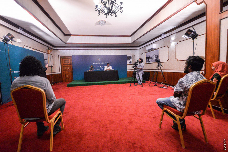 މާޗް 27، 2020: ކޮވިޑް19ގެ ނުރައްކާ ރާއްޖެއަށް ބޮޑުވެ، މުޅި ރާއްޖޭގައި ސިއްހީ ކުއްލި ނުރައްކާ އިއުލާން ކުރީ މި މަހުގެ 12 ވަނަ ދުވަހުއެވެ. އޭގެ ކުރިން ވެސް ކޮވިޑް19ގެ ހާލަތު އޮތް މިންވަރު ސަރުކާރުން ދިޔައީ ބުނެދެމުންނެވެ. ކޮވިޑް-19ގެ ތަރުޖާމާނެއްގެ ގޮތުގުގައި ރައީސް އޮފީހުގެ އަންޑަ ސެކްރެޓަރީ މަބްރޫކް އަބްދުލް އަޒީޒް ކަނޑައެޅުމާ އެކު ކޮންމެ ދުވަހަކު އެ ބޭފުޅާ ގެންދަވަނީ މީޑިއާތަކަށް މައުލޫމާތު ދެއްވަމުންނެވެ. ހުކުރު ދުވަސް ފިޔަވައި ކޮންމެ ދުވަަކު ދެ އިރު ޕްރެސް ކޮންފަރެންސް ދެއްވައެވެ. ހުކުރު ދުވަހުގެ ރޭ ވެސް ޕްރެސް ދެއްވައެވެ. ސަރުކާރު ބަންދުކޮށް، ކެފޭތަކާއި ރެސްޓޯރަންތުތައް ބަންދުކޮށްފައިވުމުން، ގޭގައި ތިބެގެން ގިނަ ބަޔަކު މަބްރޫކް ބާއްވާ ޕްރެސް ކޮންފަރެންސްތައް ދަނީ ބަލަމުންނެވެ. މި ފޮޓޯތަކުން މި ފެންނަނީ އެ ޕްރެސް ކޮންފަރެންސްތަކުގެ އަނެއް ފަރާތެވެ -- ސަން ފޮޓޯ/ ފަޔާޒު މޫސާ